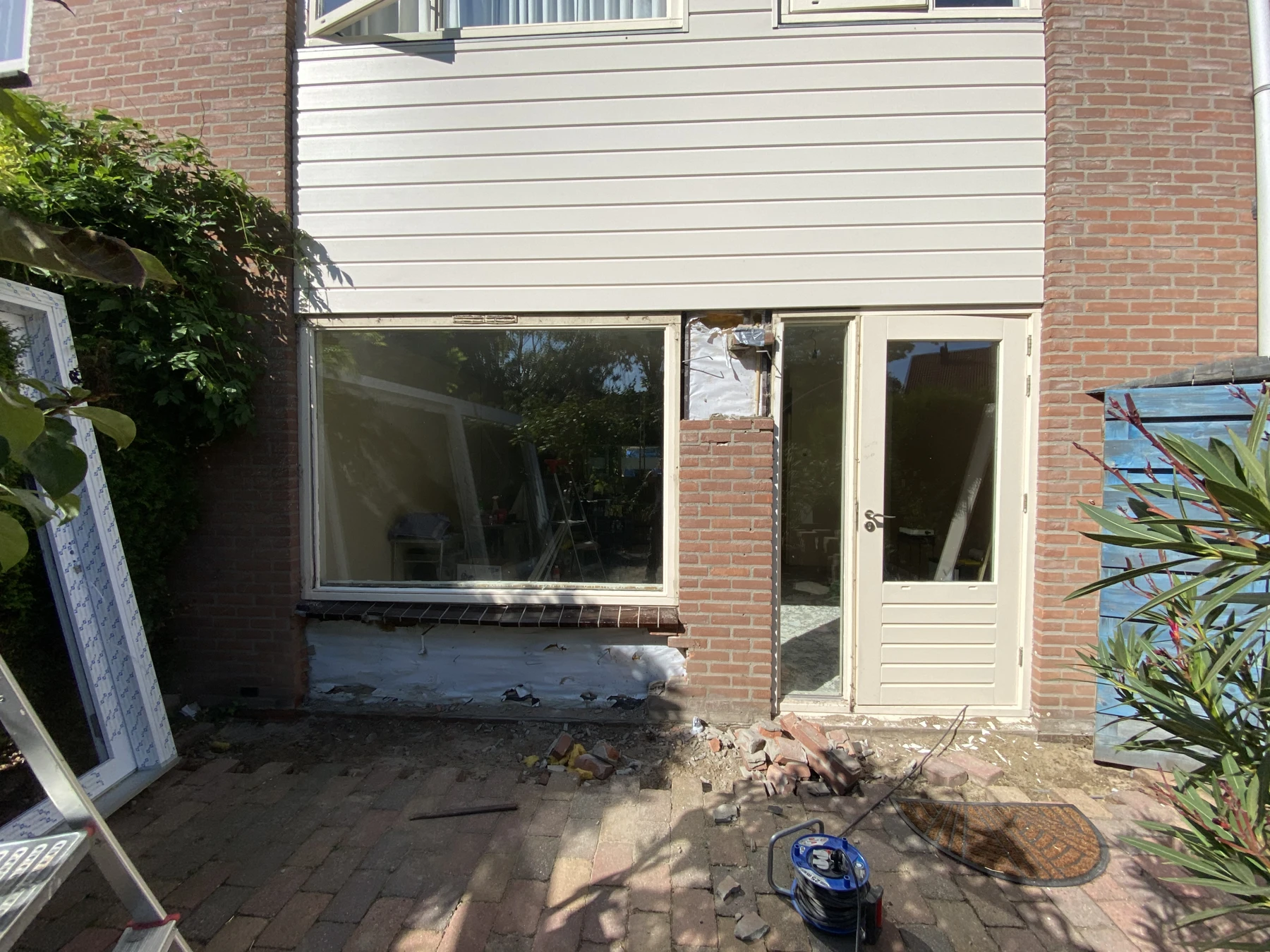 De bestaande achtergevel met een deur en vast raam in Bemmel