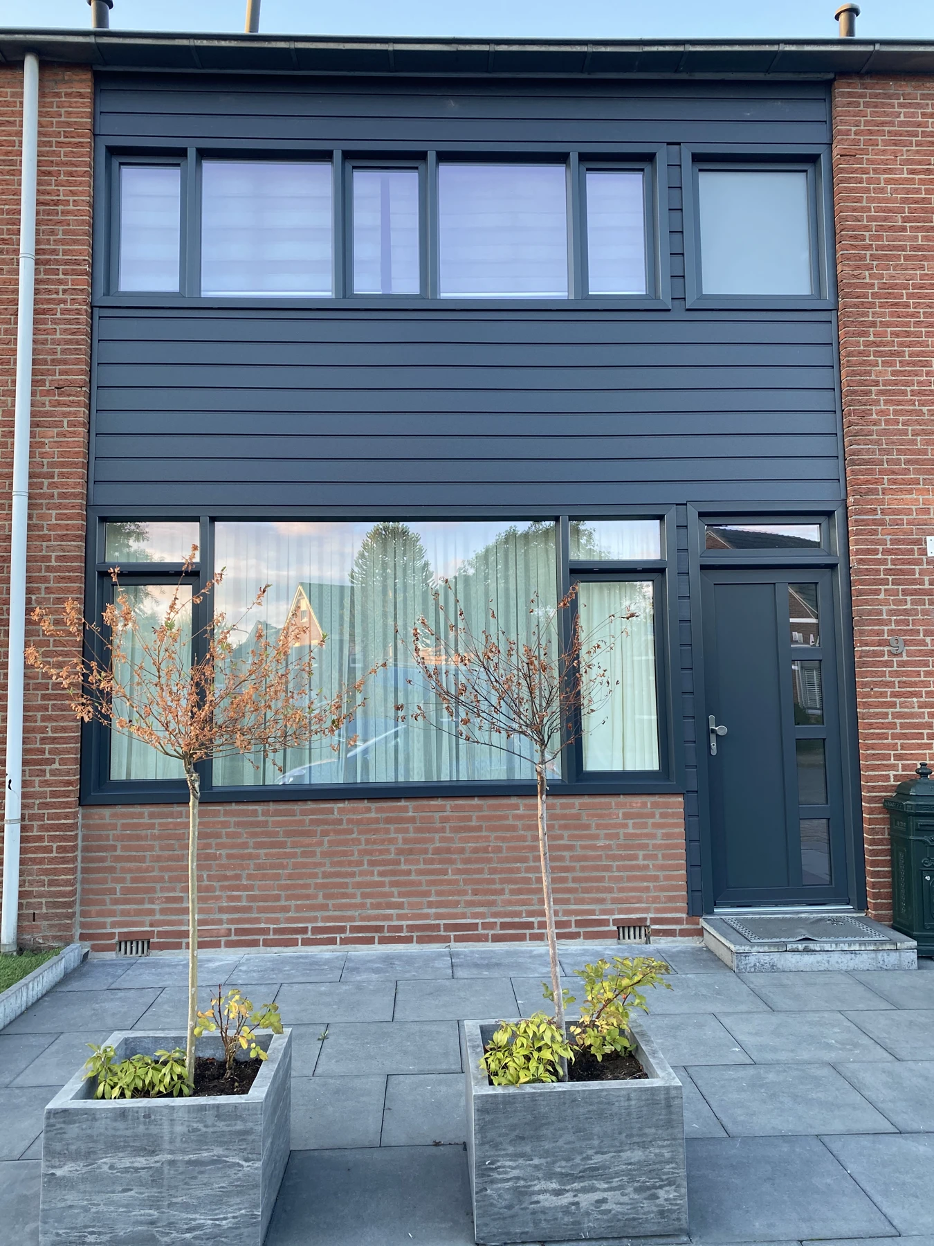 Na: gevel met antraciet kunststof kozijnen en nieuwe gevelbekleding
